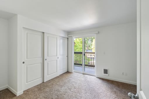 an empty living room with white doors and a balcony