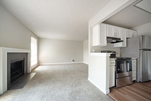 a living room with a fireplace and a kitchen with a stove and refrigerator