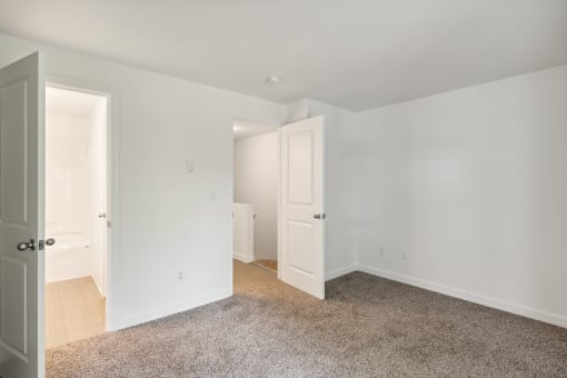 a bedroom with white walls and white doors and a carpeted floor