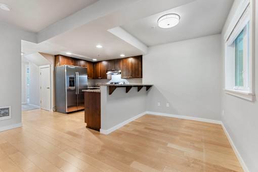 an open kitchen and living room with wood flooring and stainless steel appliances