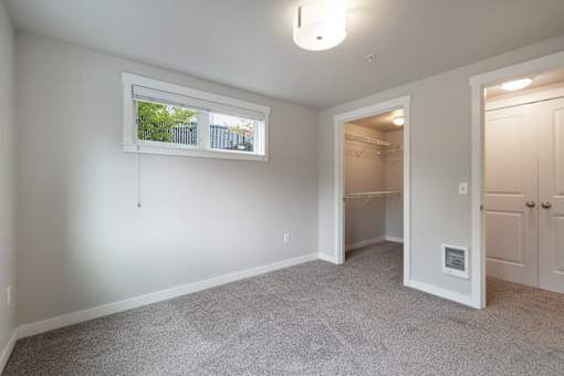 a bedroom with a closet and a window and a door to a bathroom