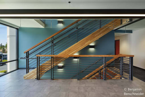 a stairwell in a building with a wood and metal railing and a blue wall behind it