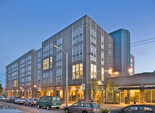 A modern multi-story building with cars parked in front.