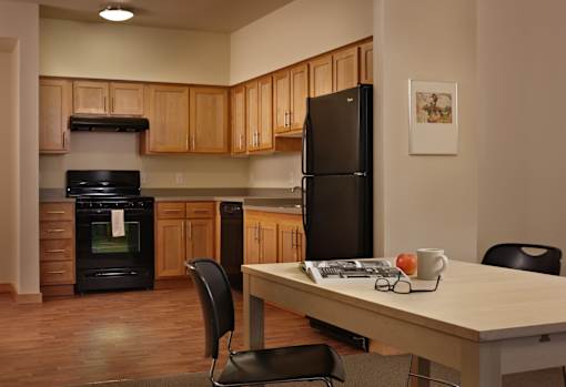 A kitchen with a black refrigerator and wooden cabinets.