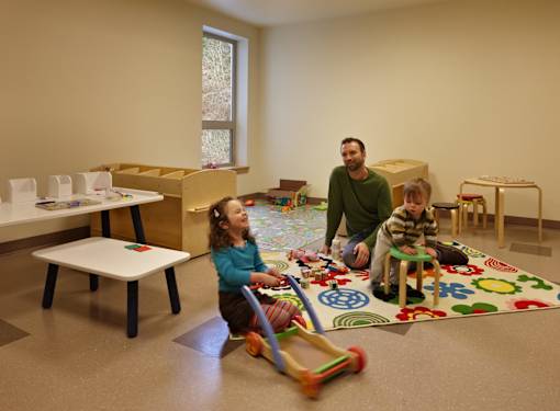 A man and two children playing with toys in a room.