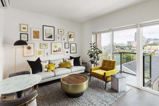 a living room with a white couch and yellow chairs and a large window