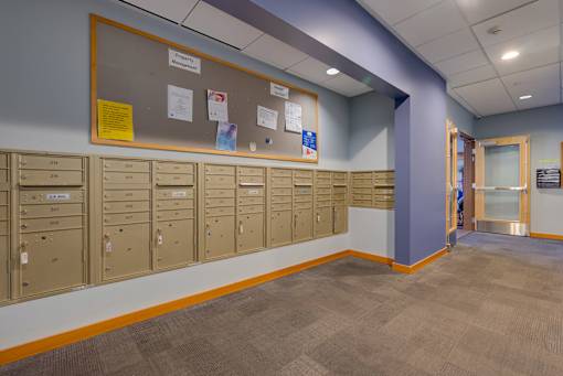A hallway with a row of lockers on the wall.