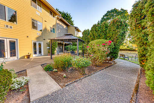 A yellow house with a gravel driveway and a small garden area.