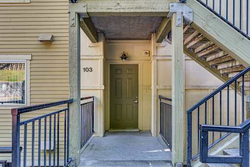 A yellow house with a green door and a staircase leading to the entrance.