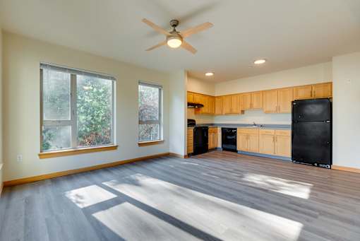 A sunny day in a spacious kitchen with a black fridge.