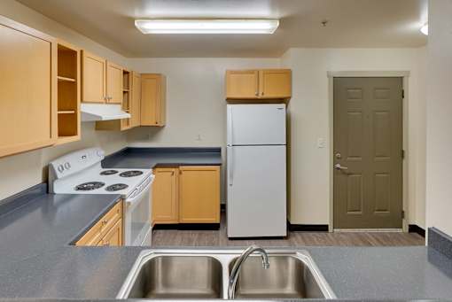 A kitchen with a stove, refrigerator, and sink.