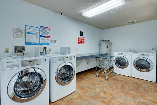 A laundry room with a row of washers and dryers.