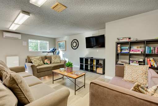 A living room with a brown couch, a coffee table, and a bookshelf.