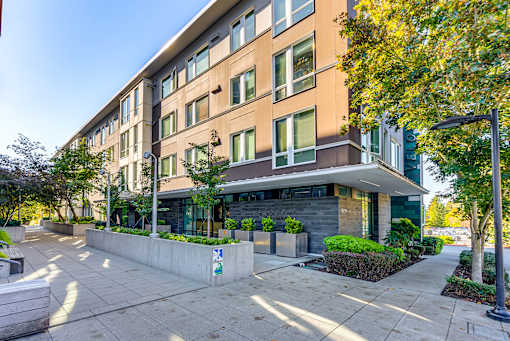 A modern building with a glass entrance and a concrete wall with a logo on it.