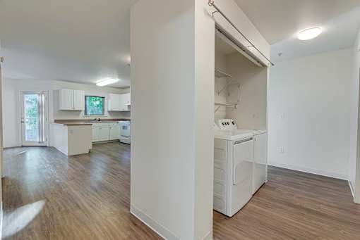 A kitchen with white appliances and wooden floors.