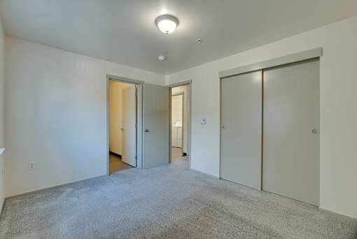A room with a carpeted floor and three doors.