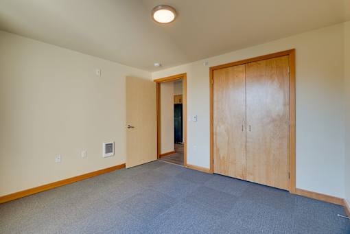 A room with a carpeted floor and a wooden door.