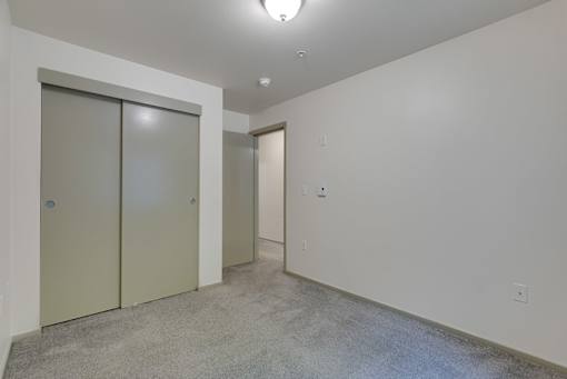 A room with a carpeted floor and two closed doors.