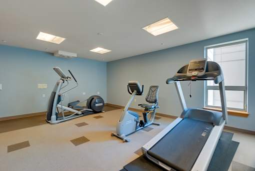 A spacious gym with treadmills, elliptical machines, and a stationary bike.