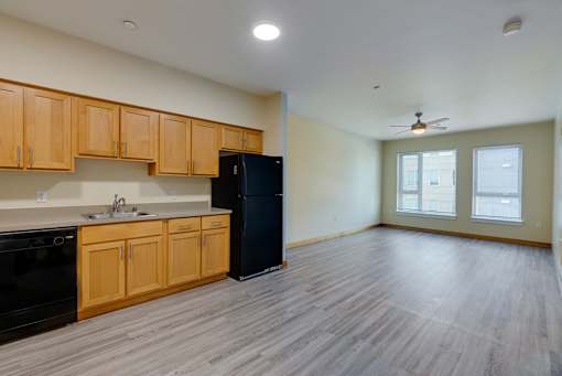 A kitchen with wooden cabinets and a black refrigerator.
