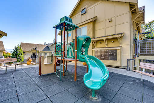 A playground with a green slide and a wooden structure.