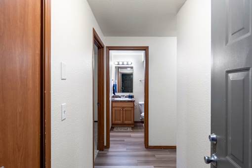 A hallway with a wooden door on the left and a grey door on the right.