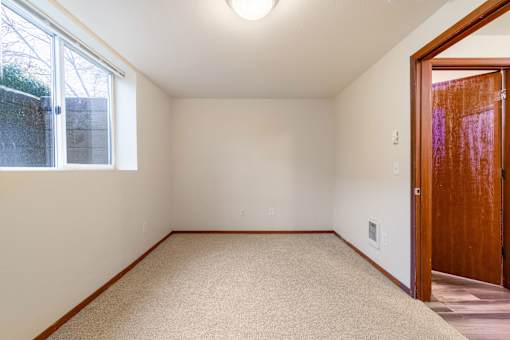 A room with a carpeted floor and a door on the right side.