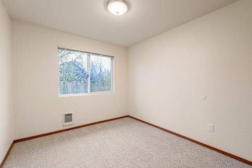 A room with a window and a carpeted floor.