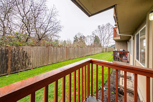 A wooden deck with a railing overlooking a backyard.