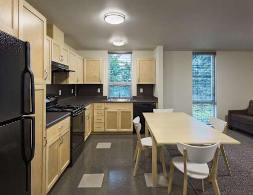 A kitchen with a black refrigerator and wooden cabinets.
