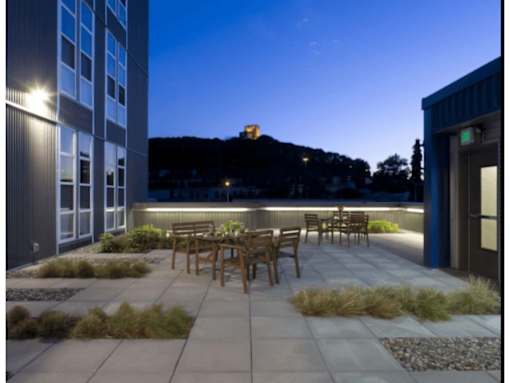 A patio with a table and chairs is lit up at night.