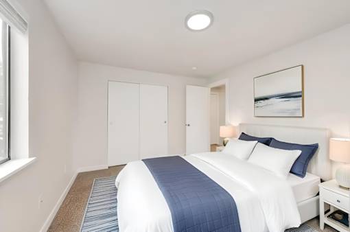 A bedroom with a large bed and a picture on the wall.