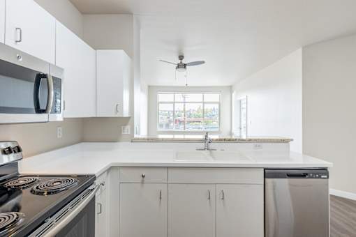 A modern kitchen with white cabinets and a stainless steel stove.