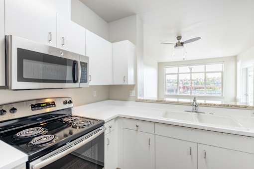 A modern kitchen with a black stove top oven and white cabinets.