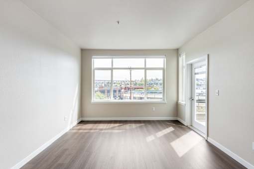 A room with a large window and wooden flooring.