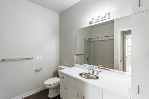 A white bathroom with a toilet, sink, and mirror.