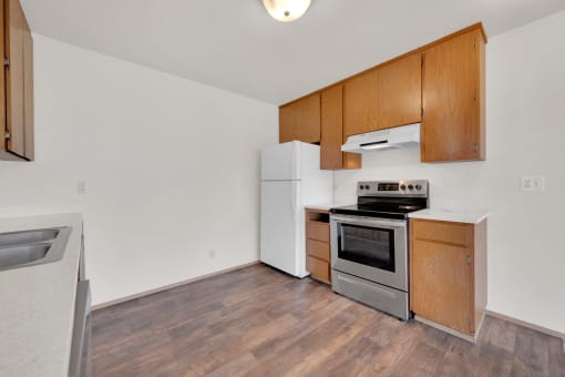 a kitchen with wood flooring and white appliances and wooden cabinets