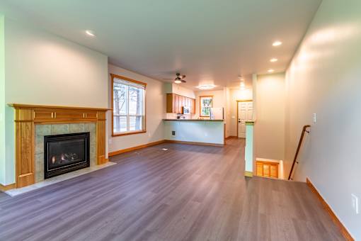 A large empty room with a fireplace and wood flooring.