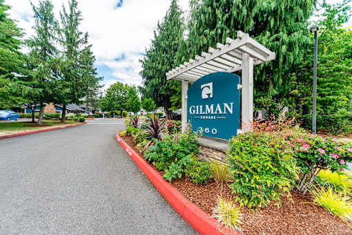 A sign that says Gilman 360 stands in front of a garden.