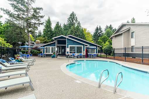 A pool with a slide and a house in the background.
