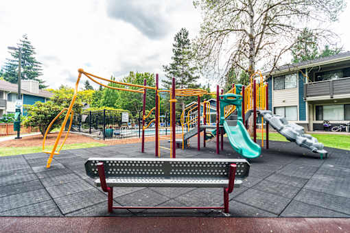 A playground with a red bench and a green slide.