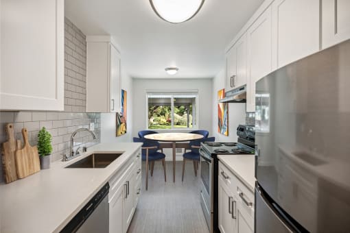 a kitchen with white cabinets and stainless steel appliances and a table with blue chairs