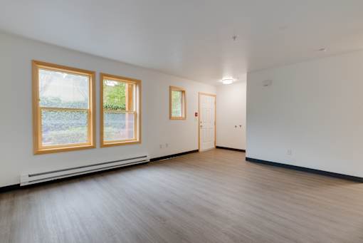 A room with wooden floors and a window with a view of trees.