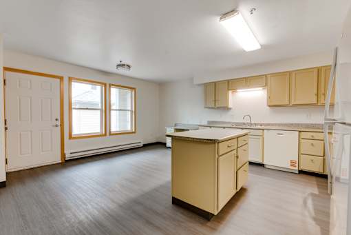 A kitchen with wooden floors and cabinets.