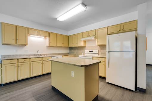 A kitchen with a white refrigerator and yellow cabinets.