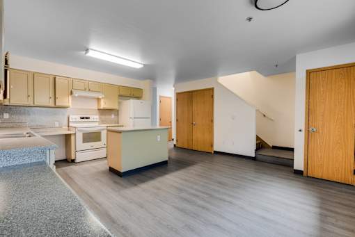 A kitchen with a refrigerator, oven, and sink.
