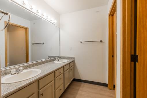 A bathroom with two sinks and lights above them.
