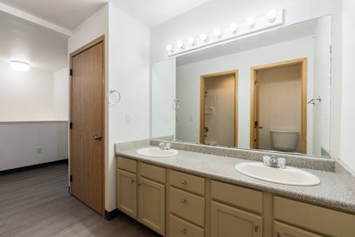 A bathroom with a sink, mirror, and wooden door.