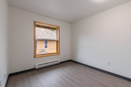 A room with a window and a heater on the floor.