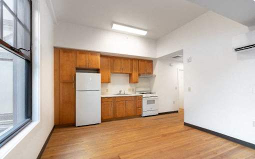 an empty kitchen with white appliances and wooden cabinets